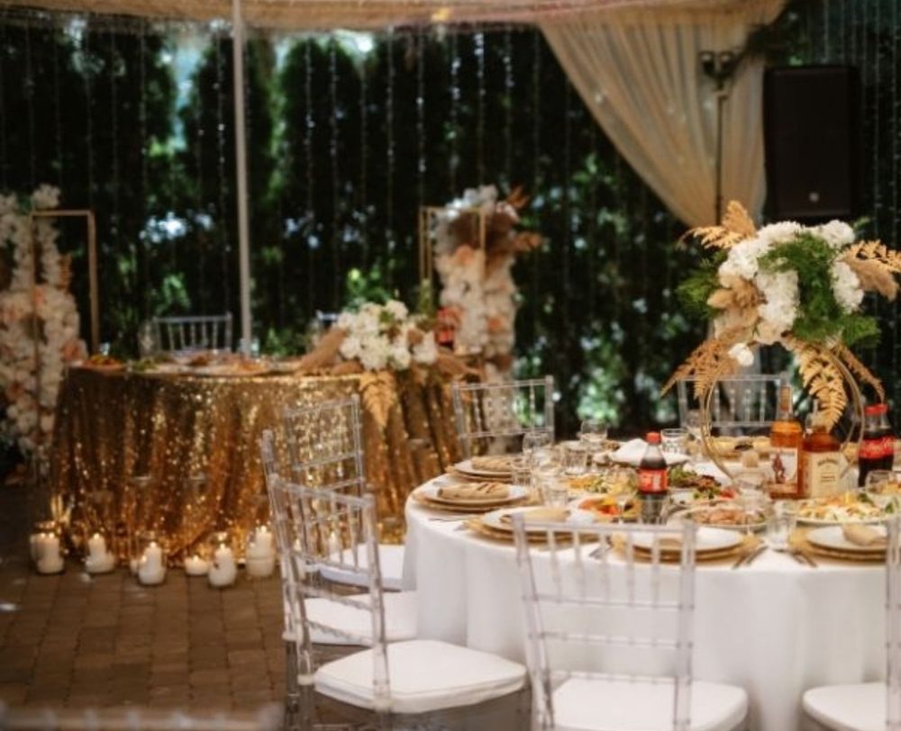Round table with a gold cloth and clear chairs in an event hall